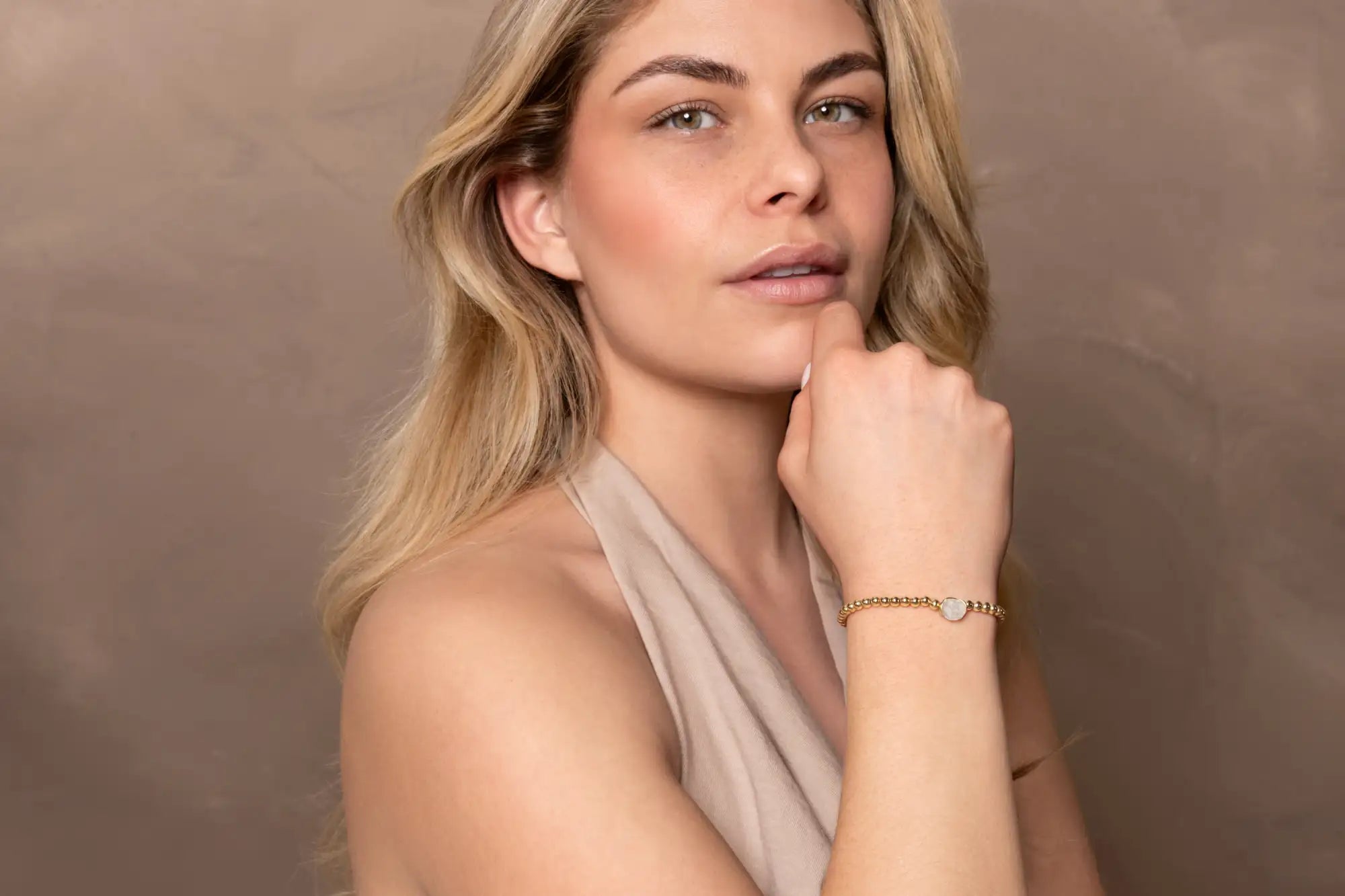 Gouden kettingarmband met een klein, rond, zilveren hanger met een gegraveerd ontwerp.